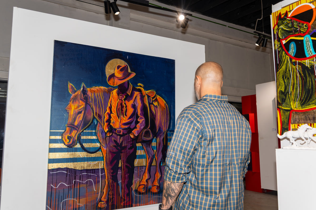 A visitor looks at a painting of a cowboy beside his horse