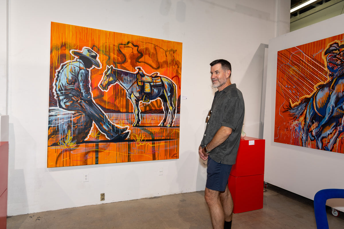 A visitor in front of an orange painting of a cowboy and horse